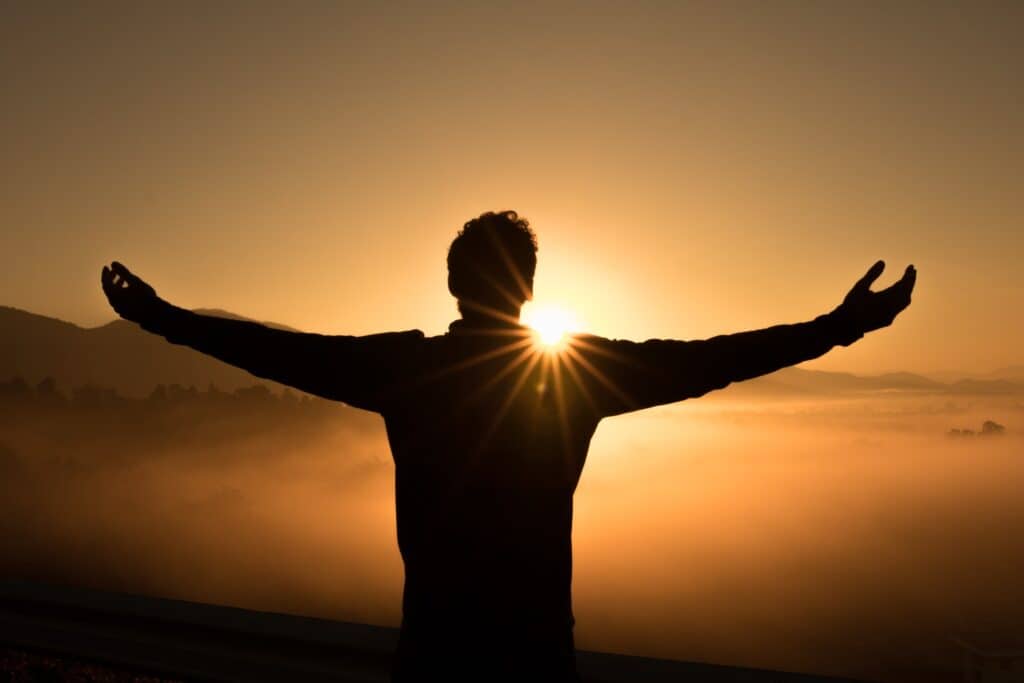 Man facing the sunset with open arms